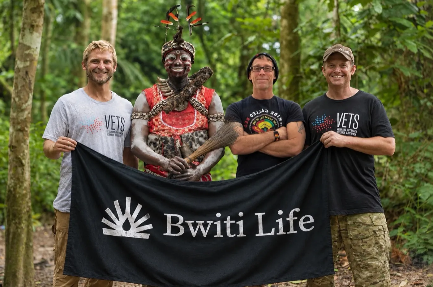 Bwiti Life practitioners with a Missoko Bwiti nganga in the forest of Gabon, holding the Bwiti Life banner